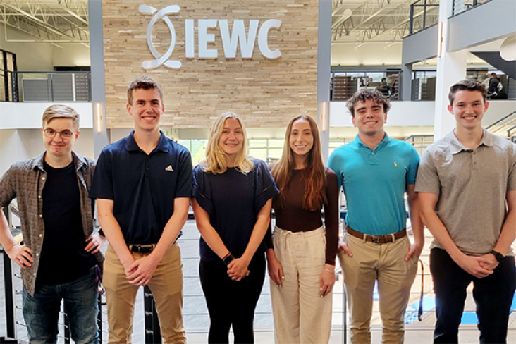 Group of students standing in front of an IEWC sign