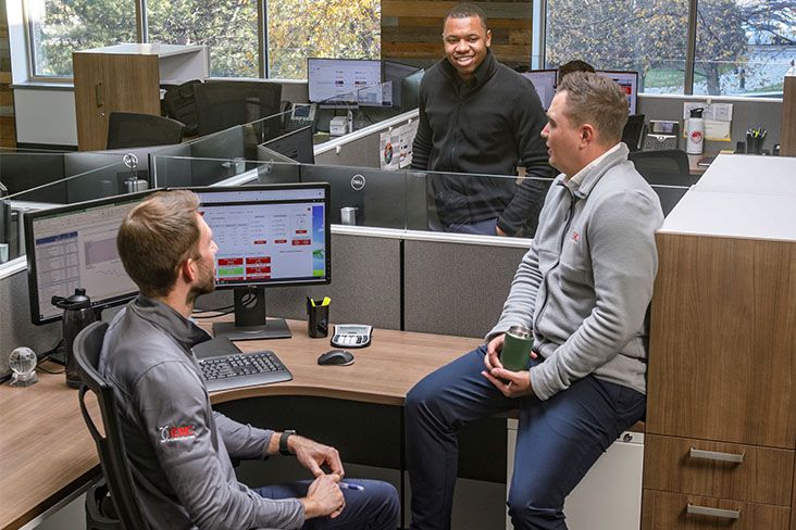 Three people sitting at a desk in an office