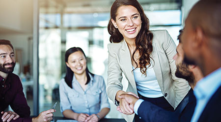 Smiling woman shaking the hand of a coworker while in a business meeting