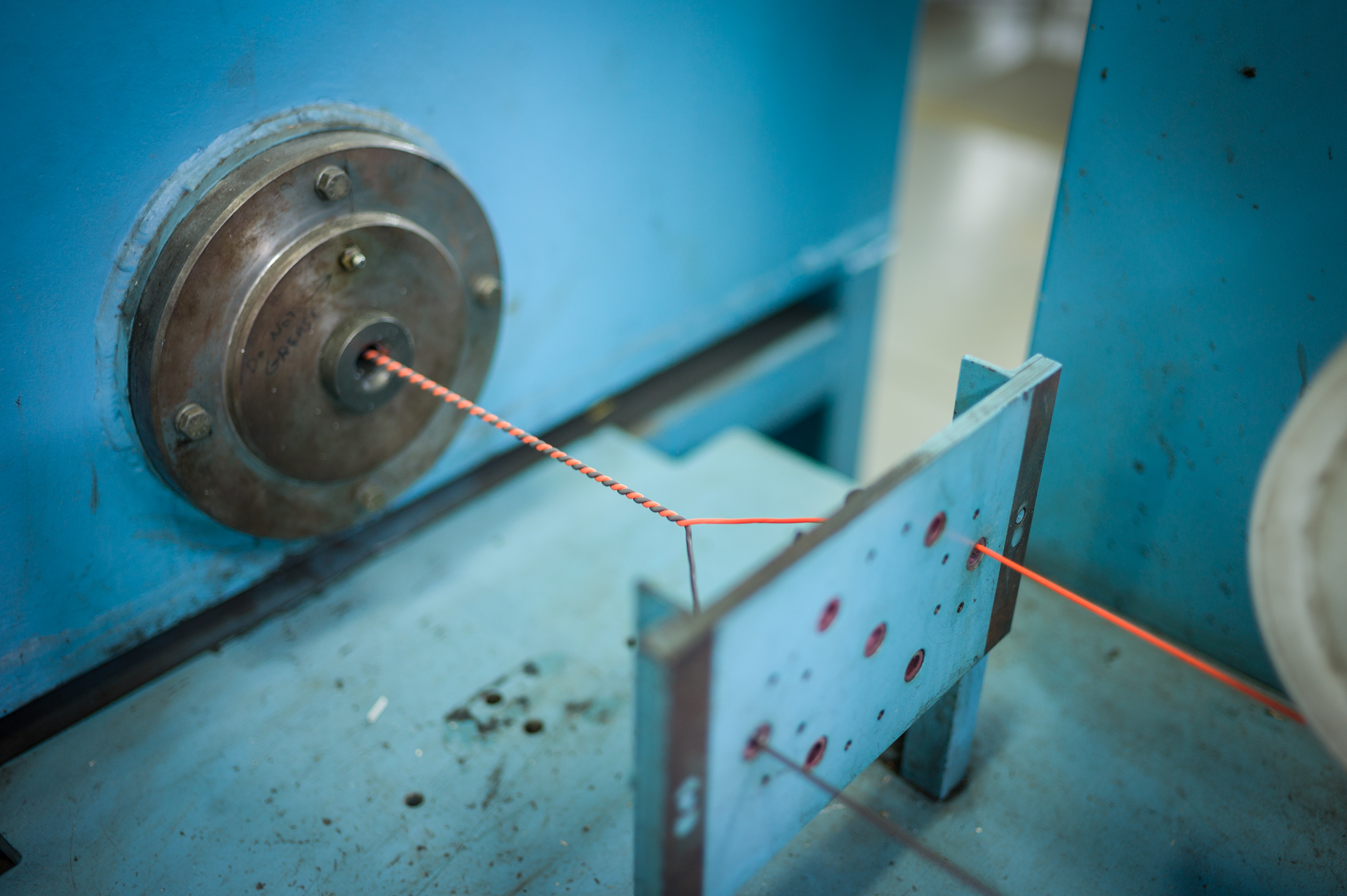 Multiple wires being twisted together by a machine.